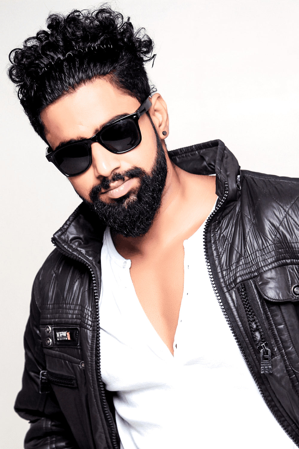 homme barbu aux poils noirs portant lunettes de soleil noires et doudoune noire